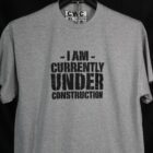 A t-shirt featuring the phrase "I am currently under construction" in bold, playful lettering, conveying a sense of humor.