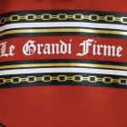 A red sweatshirt featuring the phrase "grandi firme" prominently displayed on the front.